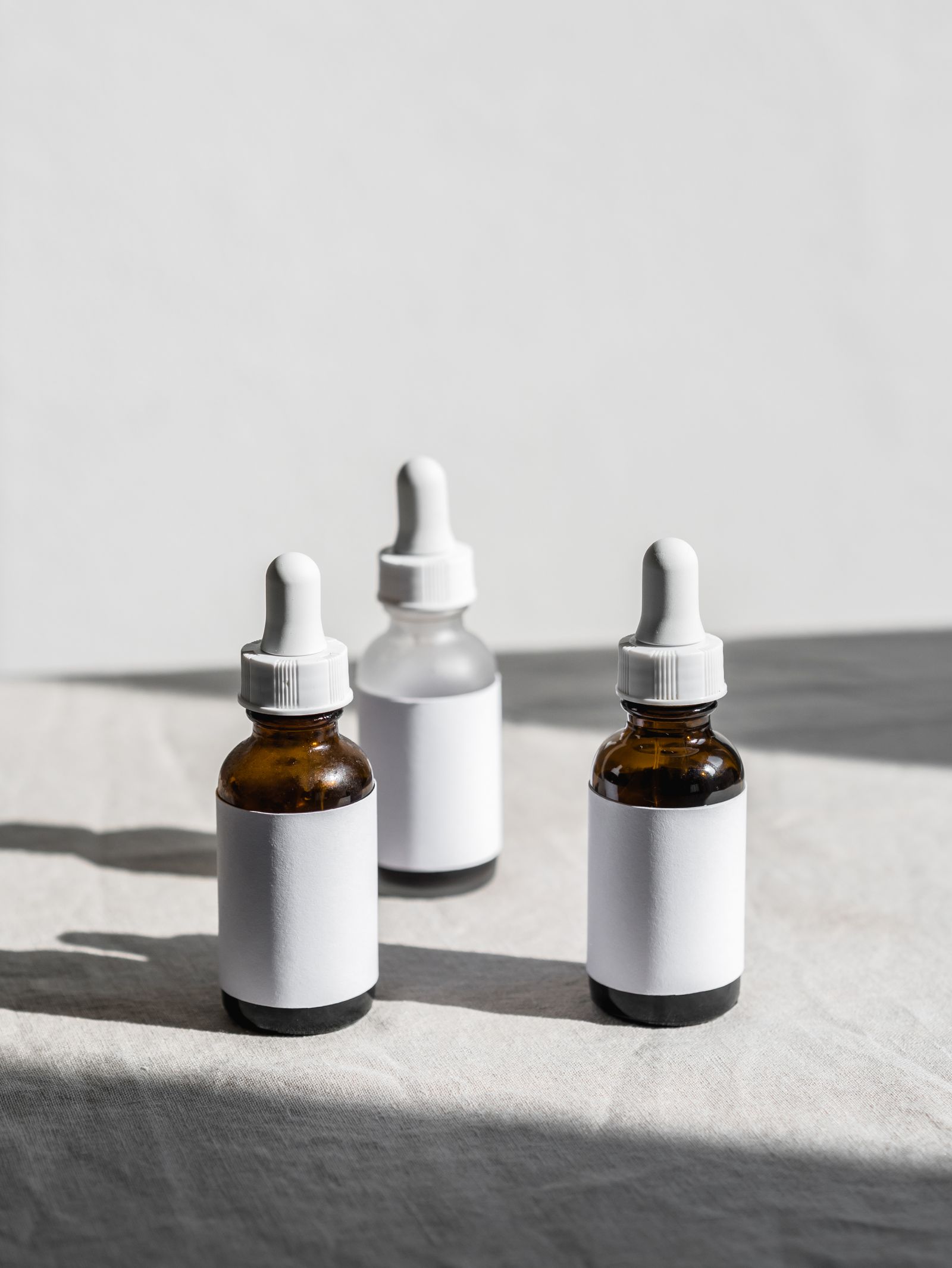 Three unbranded serum bottles in soft sunlight
